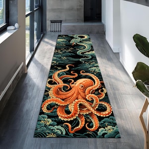 Op de afbeelding: Een lang, rechthoekig tapijt met een feloranje octopus met wervelende tentakels, tegen een zwarte achtergrond met turquoise en witte golf- en wolkenpatronen. Er is ook een groene slang afgebeeld. Het tapijt ligt in een gang.