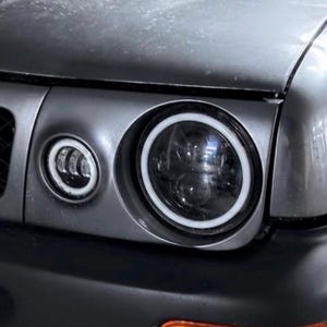 Può includere: Primo piano della parte anteriore di un'auto grigia con fari personalizzati. I fari hanno un design circolare con un anello LED bianco. L'auto presenta una griglia nera con un emblema rosso "GT R". La carrozzeria dell'auto è grigia.