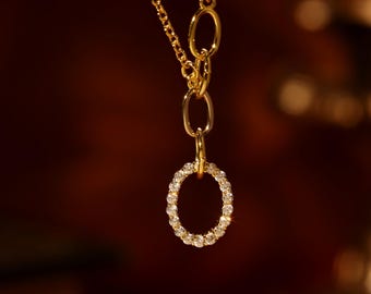May include: A gold chain necklace with a pendant featuring a circle of small sparkling stones.