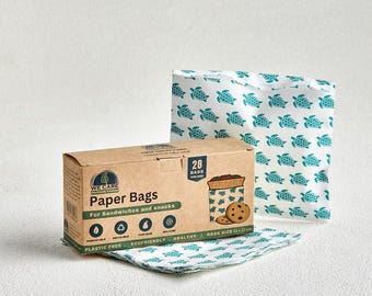 May include: A brown cardboard box containing 28 paper bags for sandwiches and snacks, featuring a teal turtle pattern. The box displays the text "We Care," "Paper Bags," and "Bags Size 15 x 17 cm." Several white paper bags with the same teal turtle print are visible.