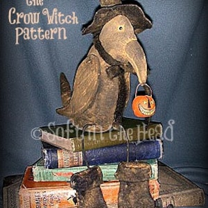 May include: A crow witch doll wearing a black hat and holding a small orange jack-o'-lantern. The doll is sitting on a stack of vintage books. The text "Miz Titch the Crow Witch Pattern" is written above the doll.