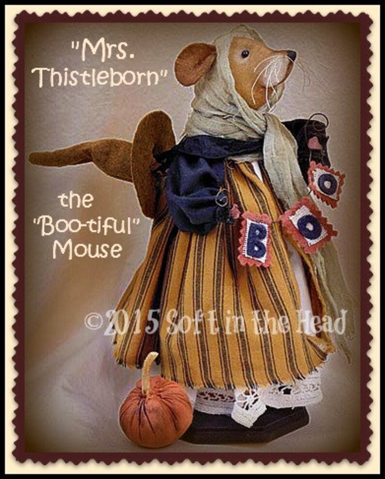 Peut inclure: Une poup&eacute;e souris artisanale, "Mrs. Thistleborn", v&ecirc;tue d'une robe ray&eacute;e orange et noire, d'un ch&acirc;le bleu et d'un foulard. La poup&eacute;e tient une banni&egrave;re "BOO" et a une petite citrouille. Le texte "the 'Boo-tiful' Mouse" est &eacute;galement visible.
