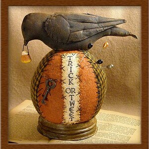May include: A Halloween-themed pincushion with a dark grey crow on a pumpkin-shaped base. The pumpkin is orange and plaid with the words "TRICK OR TWEET". The crow holds candy corn in its beak. The base has a metal rim.