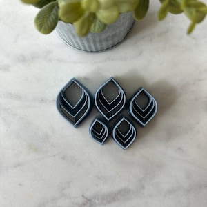 May include: A set of six blue plastic leaf-shaped cookie cutters of varying sizes.