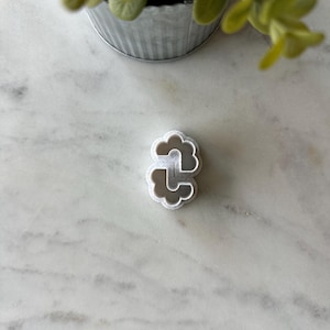 May include: White plastic cookie cutter shaped like two clouds connected together.