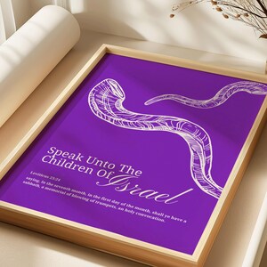 May include: A framed print with a purple background and white text that reads "Speak Unto The Children Of Israel." The image features a stylized illustration of a shofar. The frame is made of light-colored wood.