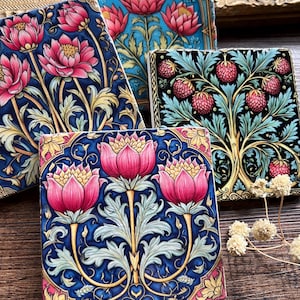 May include: Four square ceramic tiles with floral designs. Each tile features a different floral pattern with pink, blue, green, and gold accents. The tiles are perfect for adding a touch of vintage charm to any space.