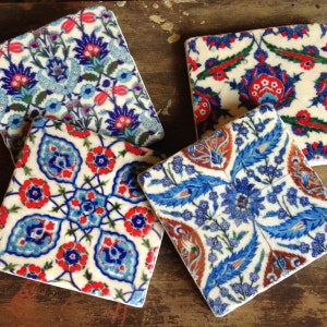 May include: Four square ceramic coasters with intricate blue, red, and white floral patterns. The coasters are made in a traditional Turkish style.