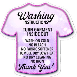 May include: A purple t-shirt shaped tag with pink glitter outlining the edges. The tag has white text that reads "Washing Instructions" and lists instructions for washing a garment: "Turn garment inside out", "Wash on cold", "No bleach", "No fabric softener", "Tumble dry low heat", "No dry cleaning", "No iron", and "Thank You!"