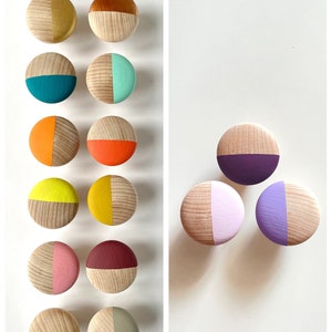 Könnte beinhalten: Ein Satz von 10 Holzgriffen in verschiedenen Farben, darunter Gelb, Orange, Rot, Rosa, Lila, Blau, Grün und Braun. Jeder Griff ist zur Hälfte mit einer kontrastierenden Farbe bemalt.