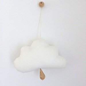 Könnte beinhalten: Ein weißes, wolkenförmiges Stofftier hängt an einer Holzperle, an der unten eine Holzregentropfe hängt.