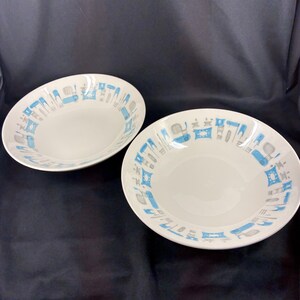 May include: Two white ceramic bowls featuring a repeating pattern along the inner rim. The design consists of stylized blue and grey kitchen appliance icons, including mixers, toasters, and coffee pots, arranged in a circular border around the center.