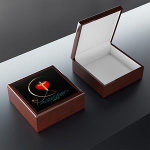 Puede incluir: Una caja de madera con un corazón rojo y una cruz dorada en la tapa. La tapa está abierta y el interior de la caja está forrado con fieltro blanco. La caja tiene un fondo negro con una cita en texto blanco. La cita dice: "El amor del Señor es eterno, su fidelidad perdura por todas las generaciones.  Salmo 100:5"
