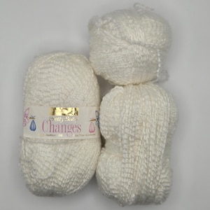 May include: Three skeins of off-white yarn. One skein has a label that reads "Pretty But Changes". The yarn has a textured appearance. The skeins are stacked on top of each other against a white background.