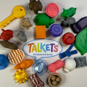 Puede incluir: Una colección de pequeños objetos de plástico coloridos que incluyen una llave amarilla, una tortuga verde, una manzana roja, un clip azul y varias figuras de animales que rodean un letrero ovalado blanco con el texto TALKETS by Speech & Smile en letras de colores.