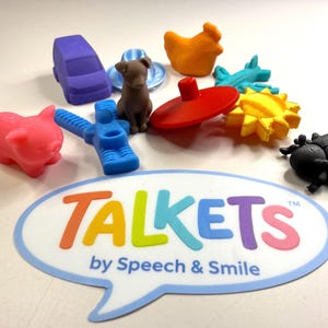 May include: A collection of colorful toy figures, including a purple car, a brown dog, an orange chicken, and a red top. The image also features a speech bubble with the word "TALKETS" in various colors and the text "by Speech & Smile".