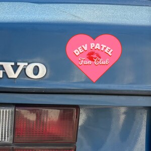 May include: A blue Volvo car trunk featuring a pink heart-shaped sticker with the text Dev Patel Fan Club and a red kiss mark. A bright green rectangular banner at the bottom displays the white text CUSTOMIZABLE! in all capital letters.