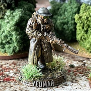 May include: A miniature figurine of a soldier in a gas mask and helmet, holding a rifle. The figure is dressed in a long coat and stands on a base with the word "YEOMAN" inscribed. The color palette is muted, with greens and browns.