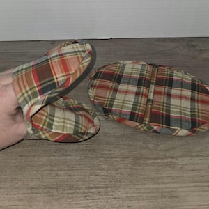 May include: A pair of plaid oven mitts. One mitt is brown, red, and beige plaid. The other mitt is brown, red, and beige plaid with a tan and beige plaid lining.