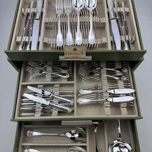 Peut inclure: Un coffret de rangement vert olive à trois niveaux contenant un ensemble complet de couverts en argent. Les tiroirs présentent des compartiments organisés pour les fourchettes, couteaux et cuillères, avec une plaque dorée Christofle Paris.