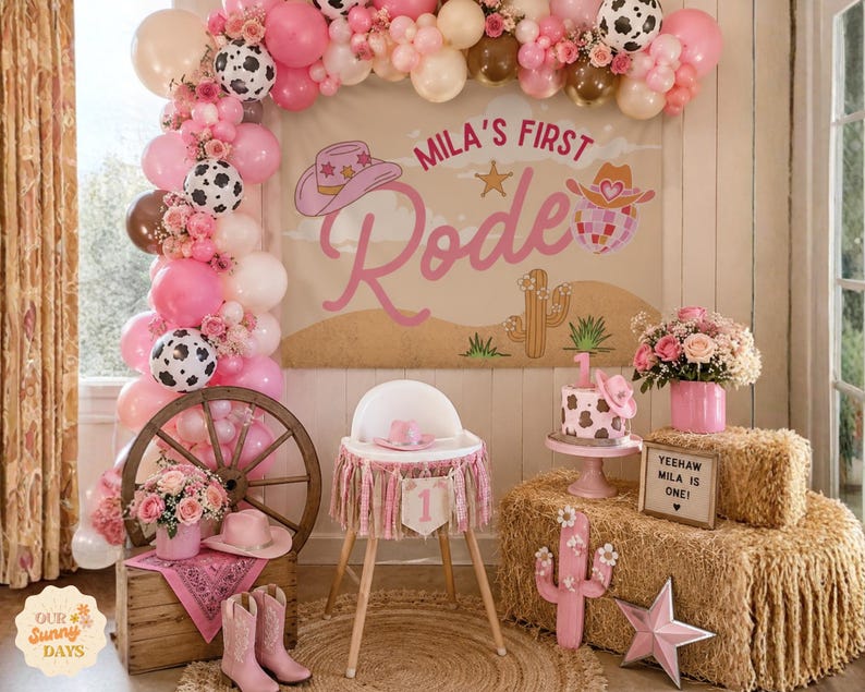 Puede incluir: Un conjunto de decoraci&oacute;n de fiesta con una pancarta con el texto Mila's First Rodeo, un arco de globos rosa y blanco, una trona con una pancarta de n&uacute;mero uno, un pastel con estampado de vaca, una rueda de madera, botas vaqueras y heno.