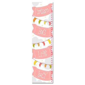 May include: Pink and white growth chart with a banner that says "Dream Big Little Lucy" and colorful flags hanging from it. The chart has a measurement scale in inches.