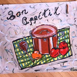 Può includere: Una tela dipinta a mano con una pentola marrone di zuppa, verdure rosse e arancioni e una tovaglia a quadri. Il testo "Bon Appétit!" è scritto in vernice nera nella parte superiore della tela.