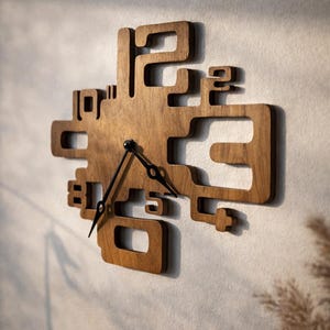 Puede incluir: Un reloj de pared de madera con un diseño geométrico único. El reloj presenta números recortados y un acabado de madera natural. Las manecillas negras indican la hora. El reloj está montado en una pared de color claro.
