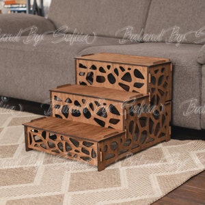 May include: Three-step wooden pet stairs with a brown stain finish. The steps have a geometric cutout design and are designed to help pets get on and off furniture.