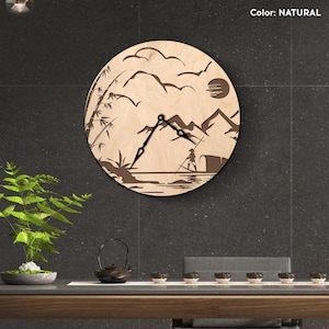 Peut inclure: Une horloge murale ronde en bois de couleur naturelle. Le cadran présente un motif découpé au laser d'un paysage de montagne avec un pêcheur, du bambou, des oiseaux et un soleil. Les aiguilles de l'horloge sont noires.