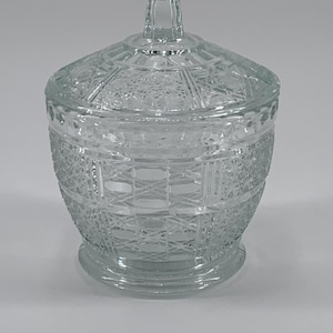 May include: A clear glass sugar bowl with a lid. The bowl and lid have a geometric pattern.