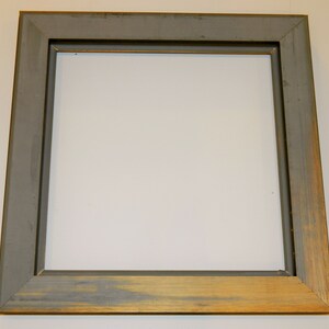 May include: A gray picture frame with a gold trim. The frame is made of wood and has a simple, classic design.