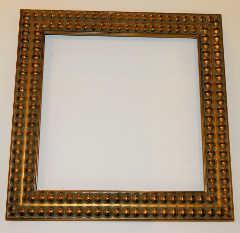May include: A gold picture frame with a beaded design around the edge.