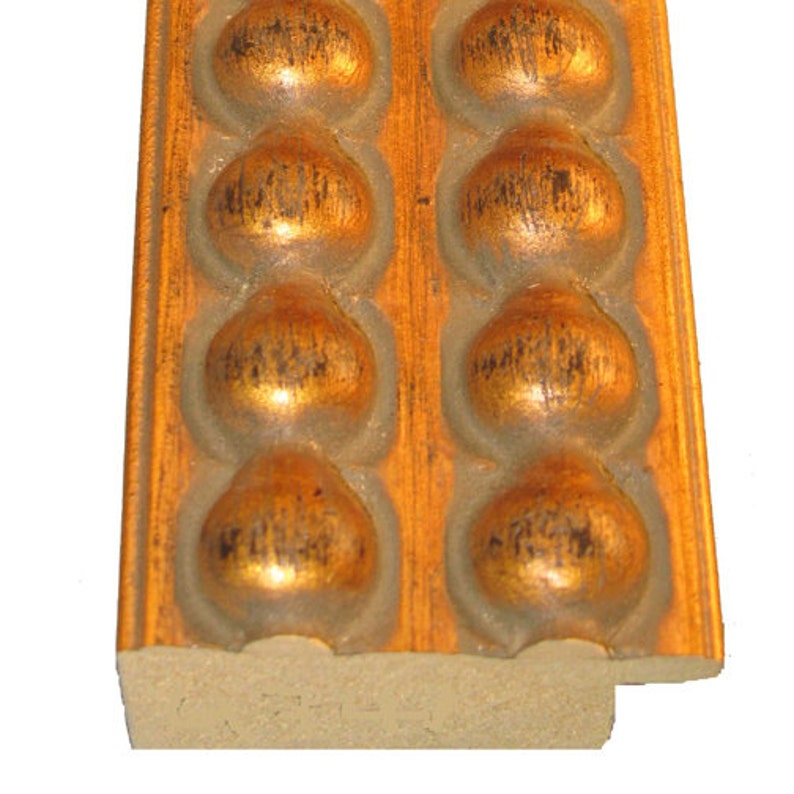 May include: A close-up of a gold picture frame with a beaded design. The frame is made of wood and has a distressed finish.