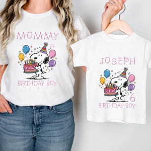 May include: White t-shirts with Snoopy birthday designs. One shirt says "Mommy of Birthday Boy" with Snoopy holding a cake and balloons. The other shirt says "Joseph 6 Birthday Boy" with a similar Snoopy design.