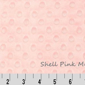 May include: Shell Pink Minky fabric with a raised dot pattern. The fabric is a soft, plush material in a light pink color. A ruler is at the bottom of the image, with measurements in inches.
