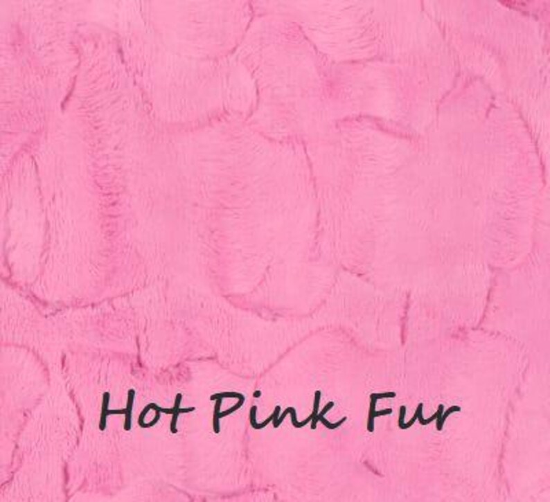 May include: A vibrant hot pink faux fur fabric with a dense, soft, and textured pile. The surface features a swirling, directional pattern characteristic of plush synthetic fur. The text Hot Pink Fur is printed in a dark font across the lower center.