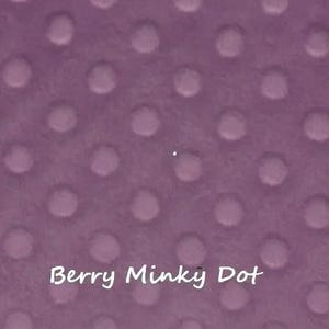 Pu&ograve; includere: Primo piano di un tessuto color bacca con un motivo a pois minky. Il tessuto ha una consistenza morbida e soffice con punti in rilievo distanziati uniformemente. Il testo "Berry Minky Dot" &egrave; scritto in corsivo bianco.