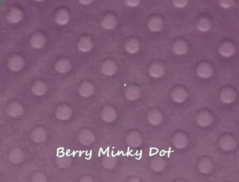 Pu&ograve; includere: Primo piano di un tessuto color bacca con un motivo a pois minky. Il tessuto ha una consistenza morbida e soffice con punti in rilievo distanziati uniformemente. Il testo "Berry Minky Dot" &egrave; scritto in corsivo bianco.