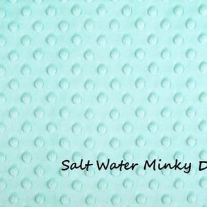 May include: A light mint green fabric featuring a raised, embossed dot pattern across the entire surface. The material has a soft, plush texture with a repeating circular design. The text Salt Water Minky Dot is printed in black.