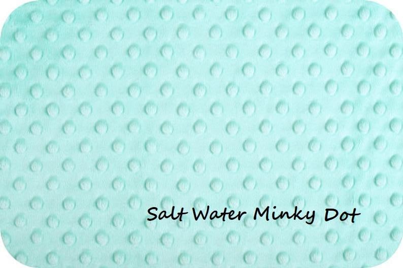 May include: A light mint green fabric featuring a raised, embossed dot pattern across the entire surface. The material has a soft, plush texture with a repeating circular design. The text Salt Water Minky Dot is printed in black.