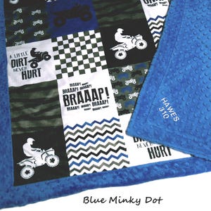 May include: A patchwork blanket featuring blue, black, white, and green squares with ATV graphics, checkered patterns, and text including A LITTLE DIRT NEVER HURT and BRAAAP. The blanket has a blue minky dot border with the text HAWES 310 embroidered.