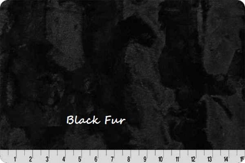 Pu&ograve; includere: Primo piano di tessuto di pelliccia nera con superficie strutturata. Le parole "Black Fur" sono scritte in bianco. Un righello &egrave; in basso, segnato in centimetri.