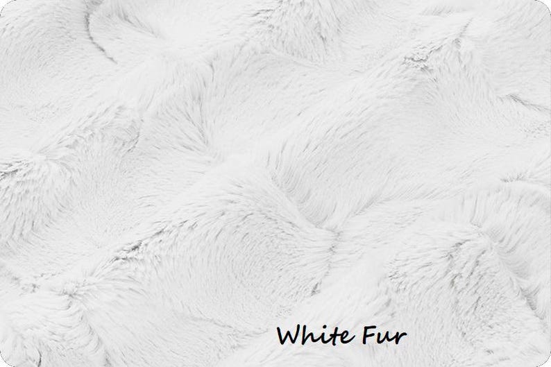 May include: Close-up of a white fur textile with a soft, textured appearance. The image shows a dense, fluffy material with a wavy pattern. The words "White Fur" are written in black at the bottom of the image.