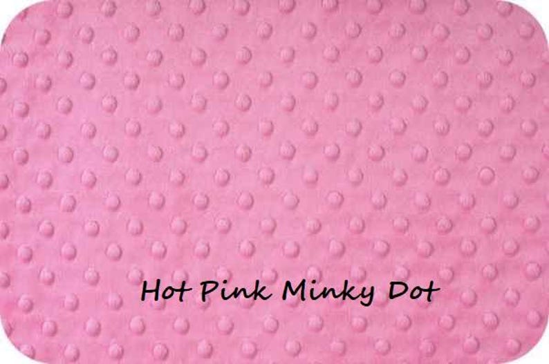Pu&ograve; includere: Un tessuto rosa acceso a pois minky con una superficie strutturata. Il tessuto presenta un motivo di piccoli pois in rilievo distribuiti uniformemente sulla superficie. Le parole "Hot Pink Minky Dot" sono scritte in nero.