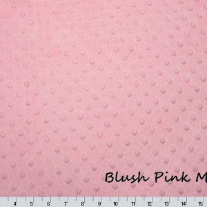 May include: Blush pink minky fabric with a textured, dotted pattern. The fabric is a soft, light pink color and has a plush feel. The text "Blush Pink Minky" is written in a cursive font across the bottom of the fabric.