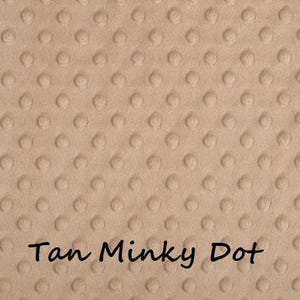 May include: Tan-colored minky dot fabric with a rounded rectangular shape. The fabric has a soft, textured surface with evenly spaced, raised dots. The words "Tan Minky Dot" are written in a cursive font at the bottom of the fabric.