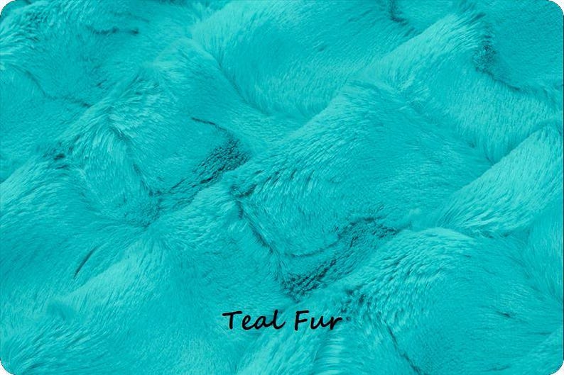 Pu&ograve; includere: Primo piano di tessuto di pelliccia color verde acqua. Il materiale in peluche ha un motivo strutturato e ondulato. Le parole "Teal Fur" sono stampate in nero nella parte inferiore dell'immagine. Questo tessuto &egrave; adatto a vari progetti di artigianato e cucito.