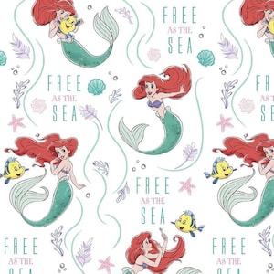 May include: White fabric featuring a repeating pattern of a mermaid with red hair and a teal tail, accompanied by a yellow fish. The phrase "FREE AS THE SEA" is interspersed throughout the design, along with starfish and seaweed.