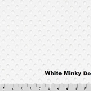 May include: A white minky fabric featuring a raised dot texture across the surface. The fabric is positioned above a ruler showing measurements in inches from 1 to 15. The text White Minky Dot is printed in black on the lower right side.
